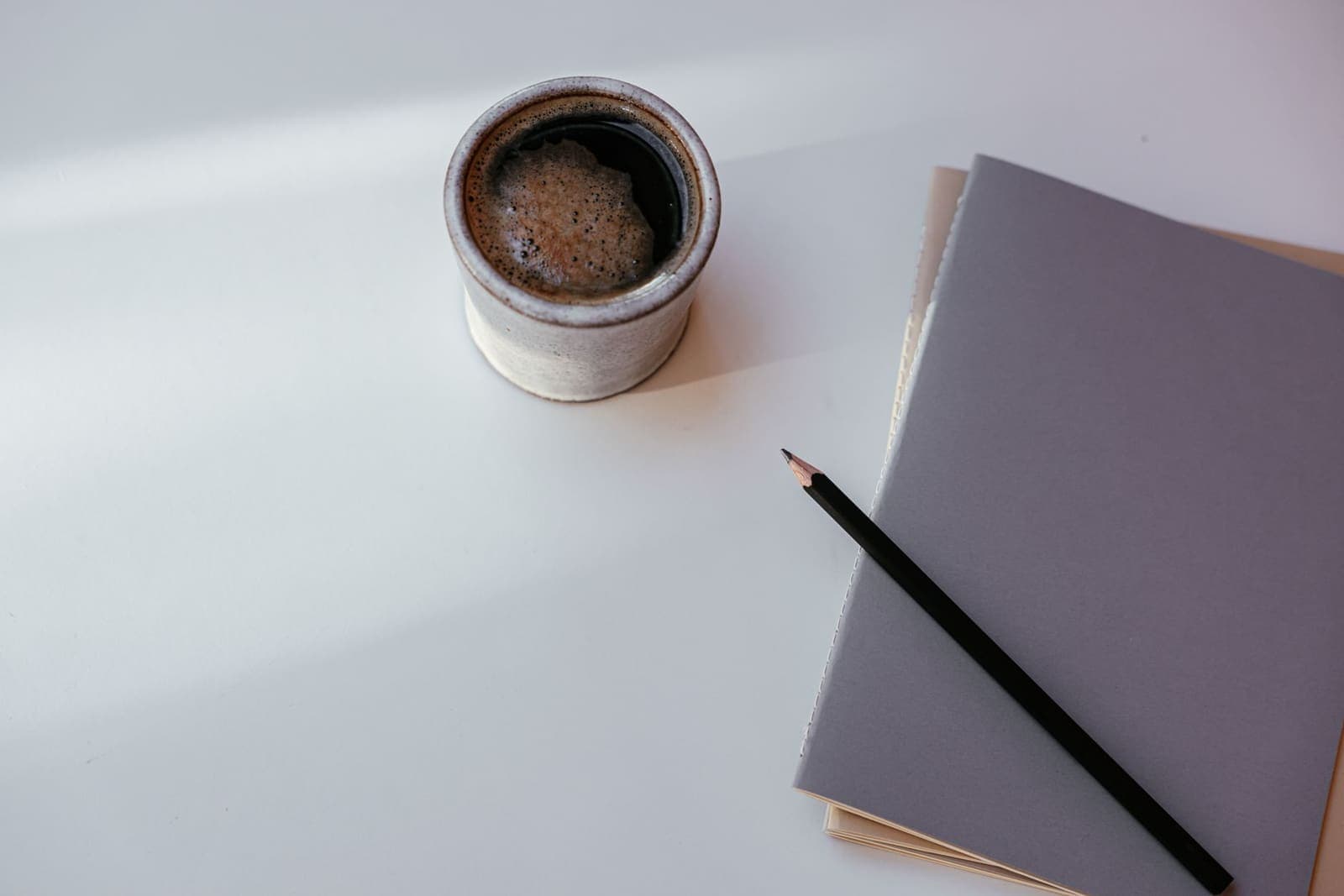 A notebook and coffee cup on a morning desk, ready for a daily planning session