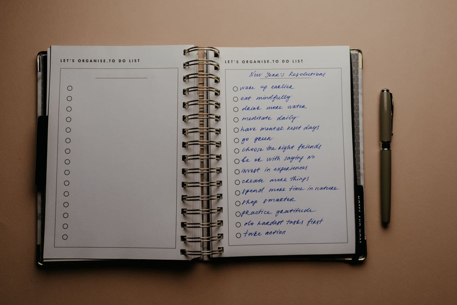 Open habit tracker journal with a pen on a wooden desk